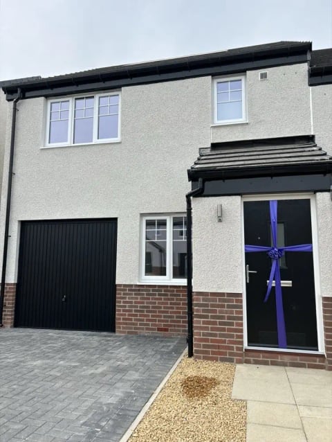 New-build house front with white render and a slate roof