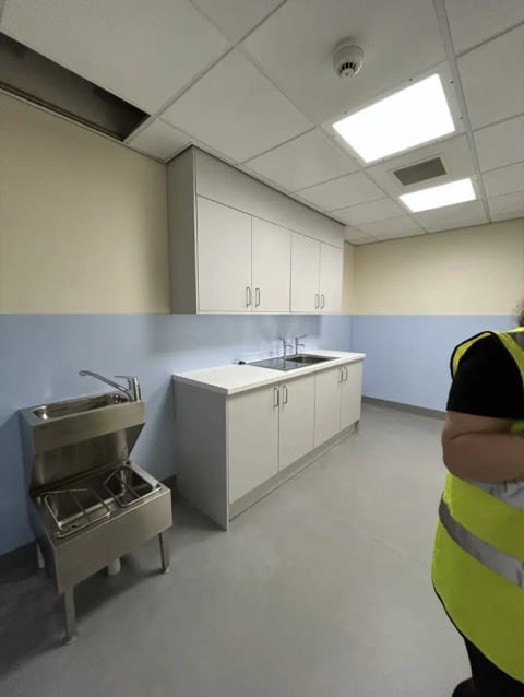 Staff kitchen with white cabinets and a stainless steel table