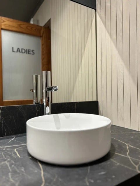Commercial washroom with a round basin and chevron tiling